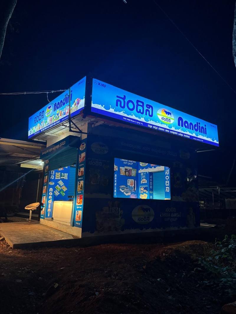 Nandini Parlour Koppalangadi dairy shop storefront in Padu, Karnataka, lit up in the evening